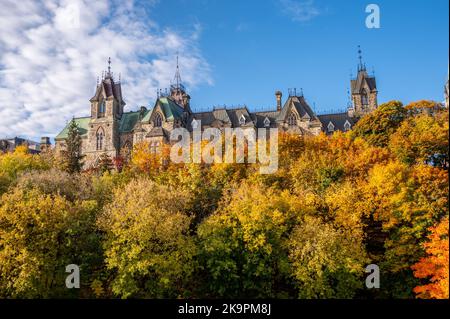 Die Türme des East Blocks auf dem kanadischen Parlamentshügel, die sich in der Ferne über den Bäumen des Rideau-Kanals erheben. Stockfoto