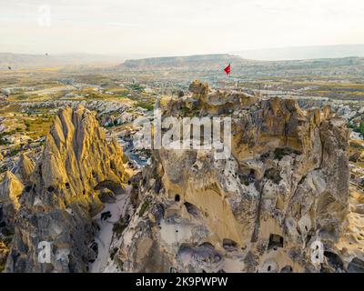 Panorama-Drohnenansicht der vulkanischen Tuffsteinformationen rund um Goreme, Kappadokien, die Zentralanatolien der Türkei, mit der türkischen Flagge auf einer der Klippen. Hochwertige Fotos Stockfoto