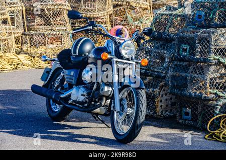 Ein schwarzes Honda Shadow Motorrad parkte vor Stapeln von Seilen und Hummertöpfen am Kai von Mudeford in der Nähe von Christchurch in Dorset, Großbritannien Stockfoto