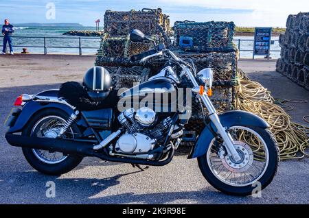 Ein schwarzes Honda Shadow Motorrad parkte vor Stapeln von Seilen und Hummertöpfen am Kai von Mudeford in der Nähe von Christchurch in Dorset, Großbritannien Stockfoto