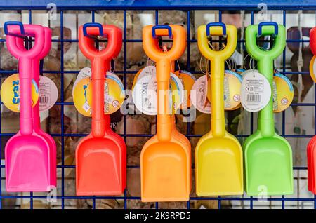 Strandspaden aus Kinderspielzeug-Plastik zum Graben in Sand auf hellen, lebendigen Farben, die in einem Geschäft am Meer ausgestellt sind. Stockfoto