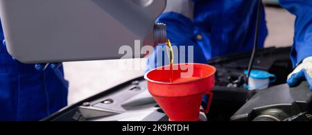 Nahaufnahme Hände von Mechaniker Mann Gießen Motoröl in Motorwagen in der Garage, Automobil wechseln Schmiermittel oder Diesel, Arbeiter nachfüllen Flüssigkeit bei Auto ser Stockfoto