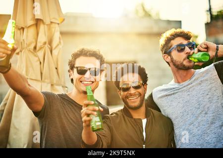Biere mit den bros. Eine Gruppe junger Freunde, die draußen herumhängen und zusammen im Freien trinken. Stockfoto