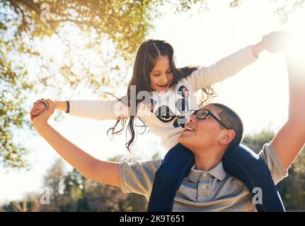 Ich bin größer als Ihr großer Bruder. Low-Angle-Aufnahme eines Teenagers, der seine entzückende kleine Schwester auf den Schultern im Freien trägt. Stockfoto