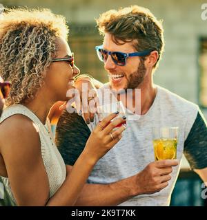 Die besten Momente im Leben werden gemeinsam gemacht: Ein attraktives junges Paar, das einen Drink zu sich nehmen und den Tag draußen auf dem Dach verbringen will. Stockfoto