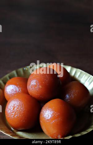 Nahaufnahme von Gulab Jamun in einer Kupferplatte auf einem Holztisch Stockfoto