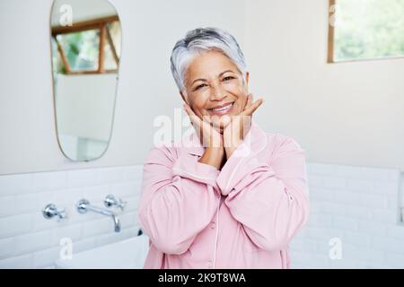 Ich bin noch eine junge Blume. Porträt einer fröhlichen reifen Frau, die ihre Hände zusammenhält, während sie tagsüber zu Hause auf die Kamera schaut. Stockfoto