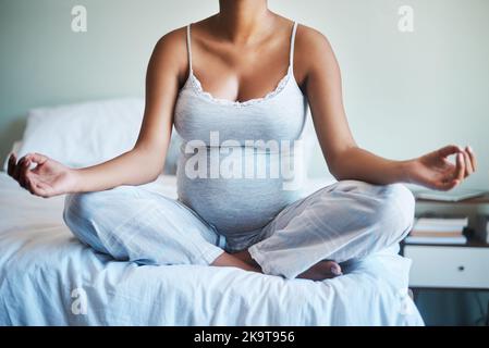 Sie brauchen all die Ruhe, die Sie während der Schwangerschaft bekommen können. Eine unkenntliche Schwangerin praktiziert Yoga in ihrem Schlafzimmer zu Hause. Stockfoto