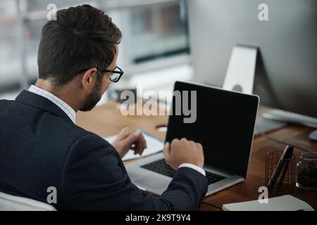 Sein Geschäft ist global geworden: Ein junger Geschäftsmann, der in einem Büro einen Videoanruf auf einem Laptop täte. Stockfoto
