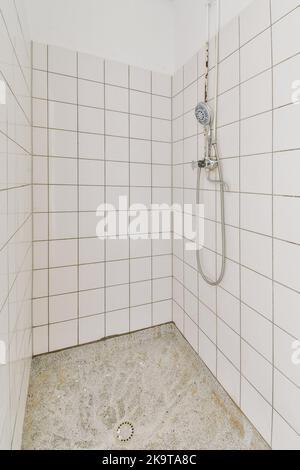 Badewanne mit Glasdusche in der Ecke neben dem Waschbecken mit weiß gefliesten Wänden Stockfoto