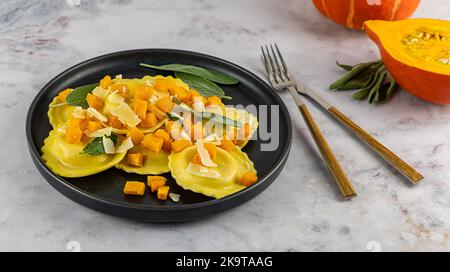 Saisonales Herbstrezept. Kürbisravioli mit Salbei, Parmesan und Olivenöl. Stockfoto