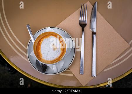 Tasse Cappuccino beim Frühstück auf einem Tisch im Freien in einem Bäckercafe in der Altstadt oder in der Vieille Ville in Nizza, Südfrankreich, von oben nach unten Stockfoto