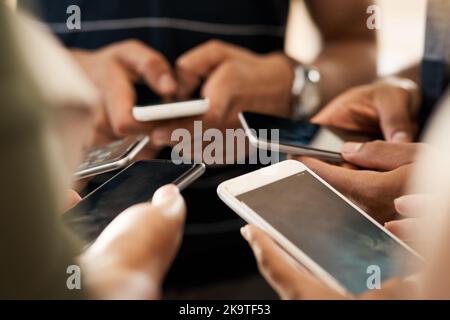 Lassen Sie sich nicht aus dem Gespräch auslassen. Nahaufnahme einer Gruppe von nicht erkennbaren Geschäftsleuten, die ihre Mobiltelefone synchron benutzen. Stockfoto