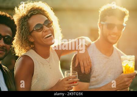 Das war eine tolle Idee, lasst es mal wieder machen. Eine Gruppe junger, vielfältiger Freunde, die einen Drink zu sich nehmen und den Tag draußen auf dem Dach verbringen. Stockfoto