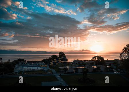 Sonnenaufgang Von Der Insel Korfu Mit Blick Auf Die Berge Der Balkanhalbinsel Griechenlands, Moraitika, Korfu, Griechenland. Im Vordergrund Sind Silhouetten Von Bäumen Stockfoto