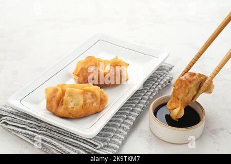 Gyoza, frittierte Knödel mit saftigem Huhn und Kohl. Serviert in weißem Teller mit Sojasauce Stockfoto
