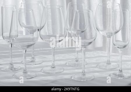 Mehrere Gläser für verschiedene Weinsorten auf der weißen Tischdecke. Stockfoto