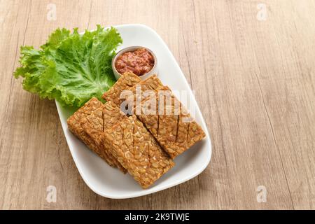 Tempeh, Tempe Goreng oder Fried Tempeh ist ein traditionelles indonesisches Essen, das aus fermentierten Sojabohnensamen hergestellt wird. Serviert mit Sambal (Chilisauce) Stockfoto