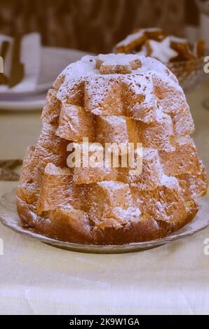 Italienische Weihnachtskuchen Pandoro auf dem Tisch mit goldener Weihnachtsdekoration. Schöne Weihnachten Essen Versammlungen Hintergrund Stockfoto