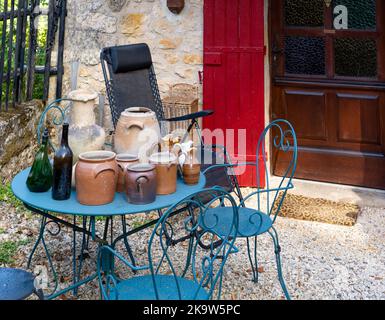 Sammlung von alten Steinguttöpfen und Flaschen auf einem blauen Gartentisch Stockfoto