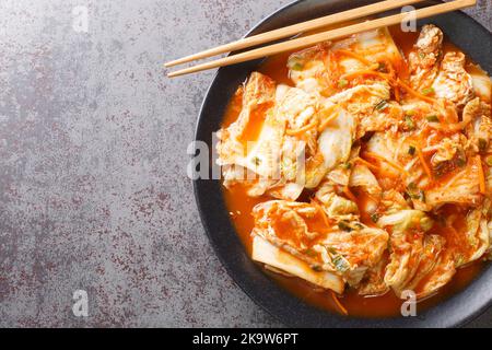 Kimchi, koreanische würzige Gemüseeinlage in Nahaufnahme in einem schwarzen Gericht auf einem Tisch. Horizontale Draufsicht von oben Stockfoto