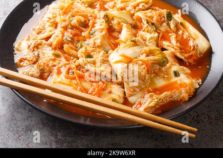 Kimchi, koreanische würzige Gemüseeinlage in Nahaufnahme in einem schwarzen Gericht auf einem Tisch. Horizontal Stockfoto