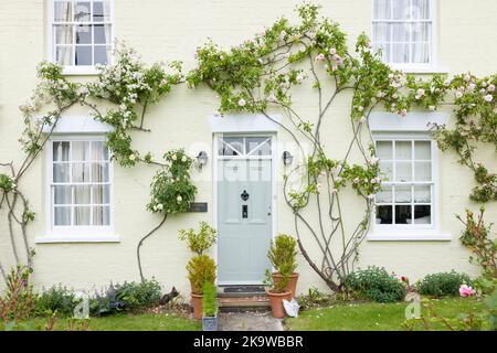 BUCKINGHAMSHIRE, Großbritannien - 03. Juni 2022. Außenansicht des Hauses Großbritannien. Englisches Haus mit grüner Eingangstür und hölzernen Schiebefenstern, umgeben von Kletterrosen. Englisch Stockfoto