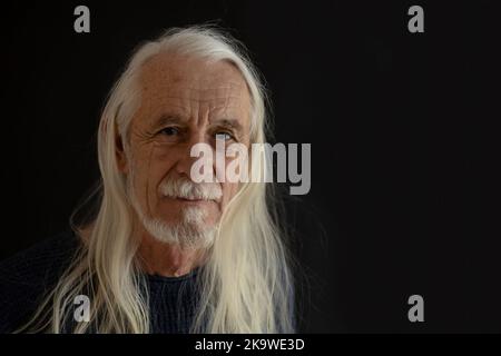 Studioporträt eines lächelnden attraktiven alten Mannes mit langen, grauen Haaren. Horizontal. Stockfoto