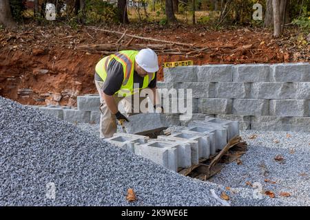 Die Fremdfirma arbeitet während der Installation einer großen Blockhalterung auf der Baustelle Stockfoto