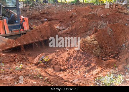 Der kleine Traktor wird verwendet, um den Boden auf der Baustelle zu bewegen und als Landschaftsmaterial zu verwenden Stockfoto