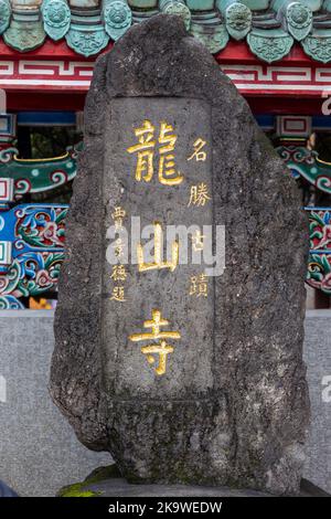 Eine Felsstele am Eingang des Longshan-Tempels in Taipei, auf der der Name des Tempels in chinesischer Sprache eingemeißelt ist. Stockfoto