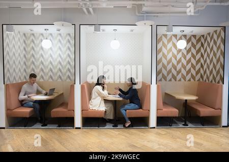 Im Coworking-Büro sitzen verschiedene Leute am Tisch Stockfoto