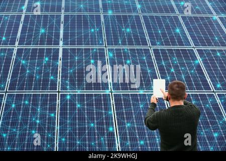 Mann mit Tablet-Computer in der Nähe von Sonnenkollektoren Stockfoto