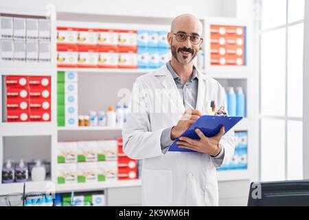 Junger hispanischer Apotheker, der auf einem Dokument in der Apotheke schreibt Stockfoto