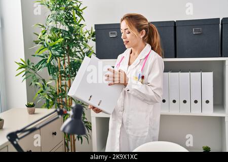 Junge Ärztin lächelt selbstbewusst und hält Bindemittel in der Klinik Stockfoto