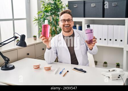Kaukasischer Zahnarzt im mittleren Alter, der Mundwasser hält, um frisch zu atmen, lächelt und lacht laut, weil er lustig verrückt ist. Stockfoto