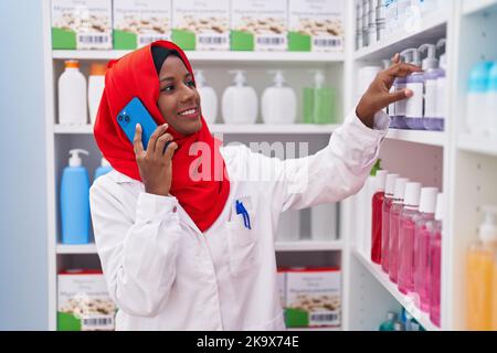 Junge schöne Frau Apotheker im Gespräch auf dem Smartphone in der Apotheke Stockfoto