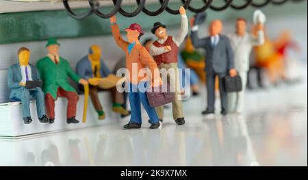 Miniatur-Spielzeug von Menschen, die mit einem öffentlichen Nahverkehrskonzept reisen - Zug oder Bus. Stockfoto