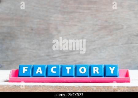 Fliesen Alphabet Buchstaben mit Wort Fabrik in roter Farbe Rack auf Holz Hintergrund Stockfoto