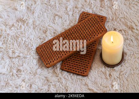 Sadhu Boards zum Stehen auf Metallnägeln mit Kerze auf hellem flauschigen Hintergrund, Draufsicht. Yoga und Meditationspraxis Konzept Stockfoto