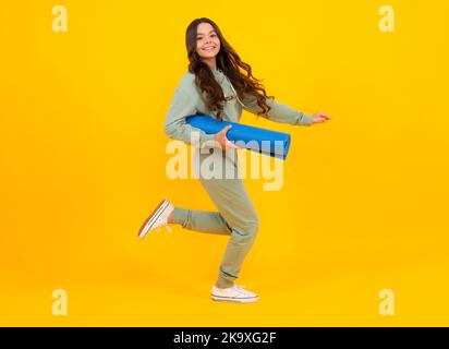 Sportbekleidung Werbekonzept. Teenager Kind Mädchen in Trainingsanzügen Jogginganzug posiert im Studio halten Fitness-Matte. Laufen und springen. Stockfoto