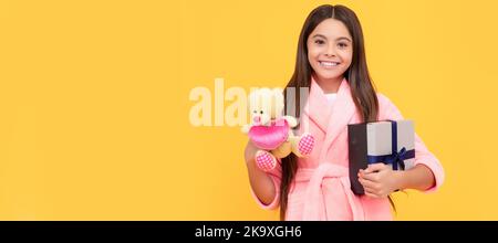 Guten Morgen. Kid tragen weichen Nachthemd spielen mit Spielzeug. Kind in gemütlichen Schlafbekleidung. Teenager-Mädchen mit Geburtstagsgeschenk, horizontales Poster. Stockfoto