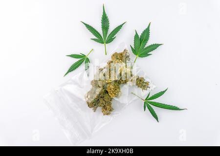 Beutel mit Cannabis-Blüten-Knospen und Marihuanablättern isoliert auf Weiß Stockfoto
