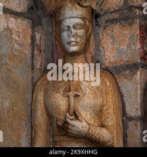 Helena von Konstantinopel oder Heilige Helena, römische Kaiserin und Mutter des ersten christlichen Kaisers Konstantin dem Großen, hält ein Kruzifix. Die 1100s-Säulen-Statue im Nordportal der Basilika Saint-Just in Valcabrère in Occitanie, Südwestfrankreich - eine der französischen Kirchen besitzt ein Bruchteil des wahren Kreuzes, das sie aus Jerusalem mitgebracht hat. Stockfoto