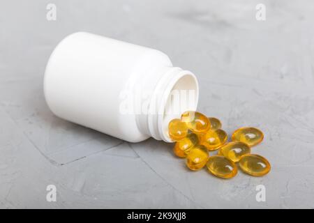 Omega-3 Kapseln liegen in einer weißen Flasche auf einem Tischhintergrund. Fischöl Tabletten Draufsicht. Biologisch aktive Zusatzstoffe. omega 6, Omega 9, Vitamin A, E, Stockfoto