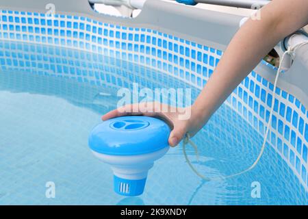 Arbeiter Hände Isinfektion und Chlorierung von Wasser in den Pool. Reinigung von Verschmutzung Pool Chlorspender. Stockfoto