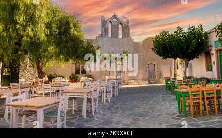 Ein Platz mit Restaurants und einem alten Kirchengebäude in der schönen Stadt Chora auf der Insel Folegandros, Kykladen, Griechenland. Stockfoto