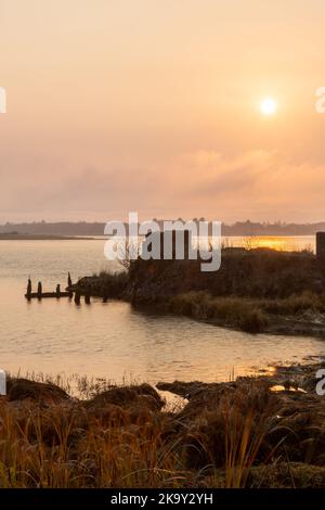 Rote Hinweise auf nebligen Sonnenaufgang durch Sturzbrände im Staat Washington. An einem nebligen Morgen über Baker Bay im Cape Disapointment State Park, WA, aufgenommen. Sta Stockfoto