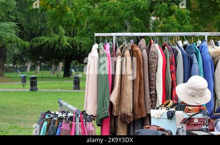 Alte gebrauchte Kleidung und neue Kleider im Stand auf dem Flohmarkt Stockfoto