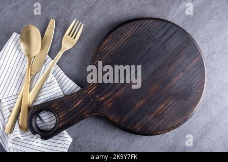 Schneidebrett aus Holz oder Servierbrett mit Serviette und Besteck Stockfoto